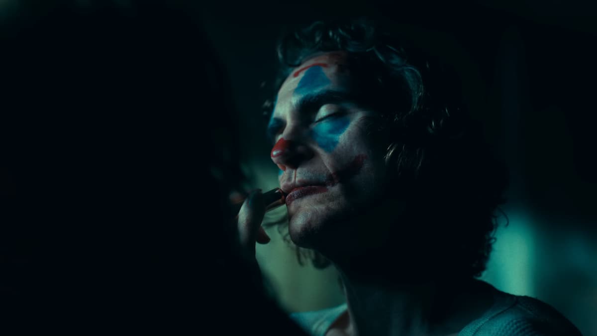 Arthur (Joaquin Phoenix) putting on his makeup in Joker: Folie à Deux